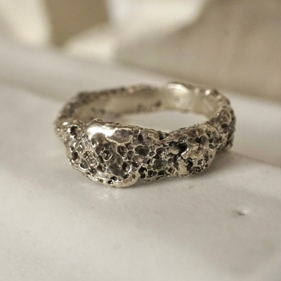 Silver ring with textured surface on a white background