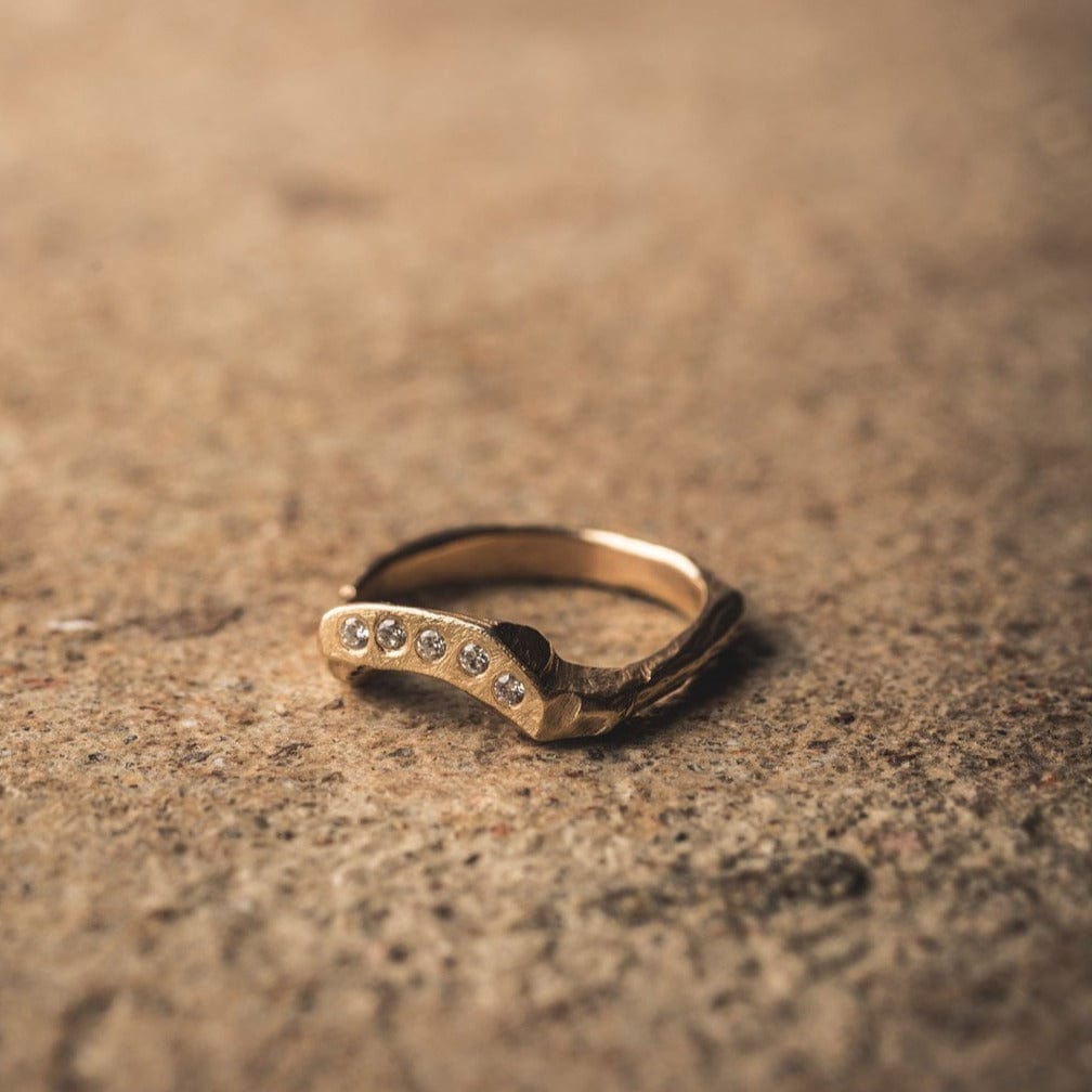 The Arcus Ring, with recycled gold and Canadian diamonds, on a textured background.