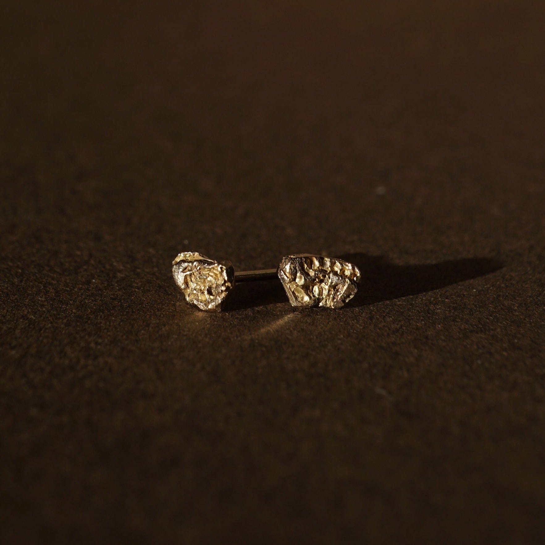Science inspired stud earrings that look like asteroids. Made of 14K yellow gold. Textured and asymmetrical design. 